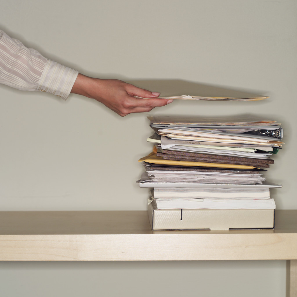 Person putting file on a stack of papers
